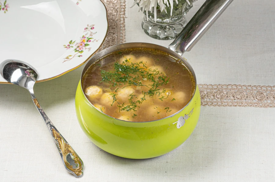 Бульон с куриными фрикадельками, домашней лапшой и перепелиным яйцом, с зеленью